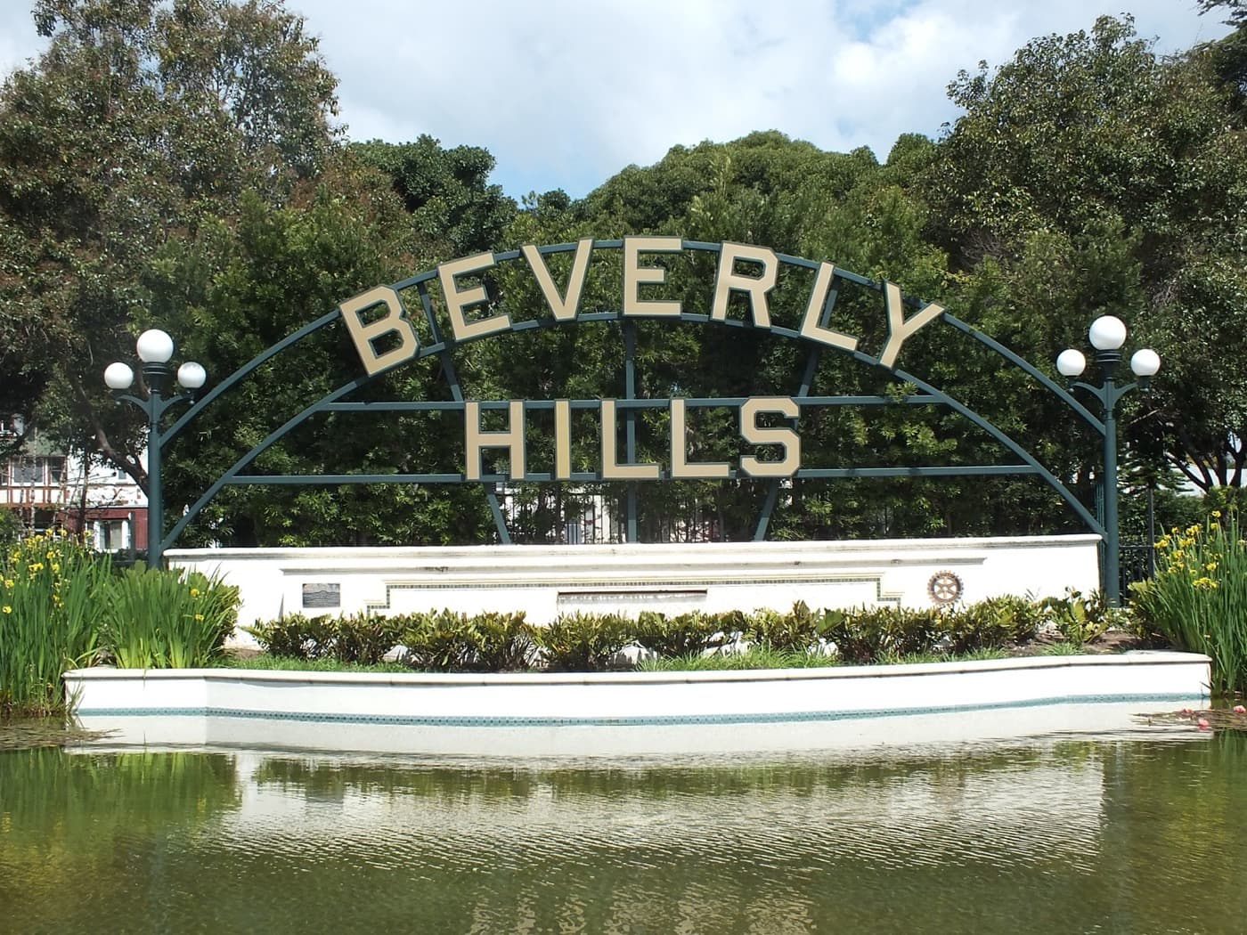 The Beverly Hills sign and lily pond framed by palms in Beverly Gardens Park